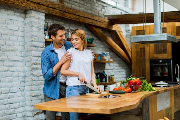 Beau couple gai, cuisiner ensemble et s&#39;amuser à la cuisine rustique