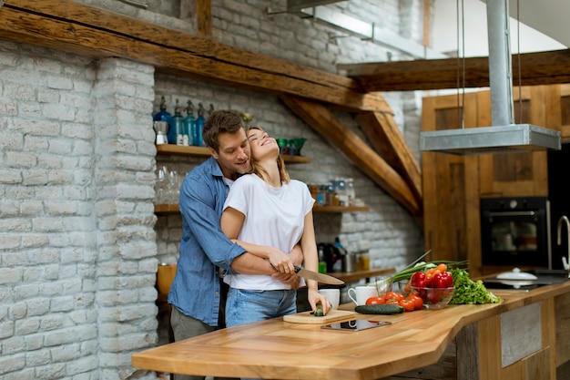 Beau couple gai, cuisiner ensemble et s&#39;amuser à la cuisine rustique