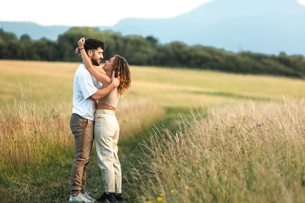 Beau couple hétérosexuel dans un champ d'herbe marchant et s'embrassant