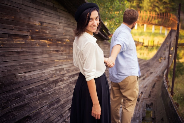 Beau couple hipster amoureux à une date en plein air dans le parc s'amuser. Homme rousse barbu. Femme brune en jupe noire et chemisier blanc et chapeau noir.