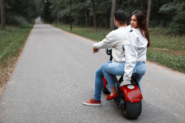 Beau couple homme et femme monter sur un vélo électrique moderne dans le parc