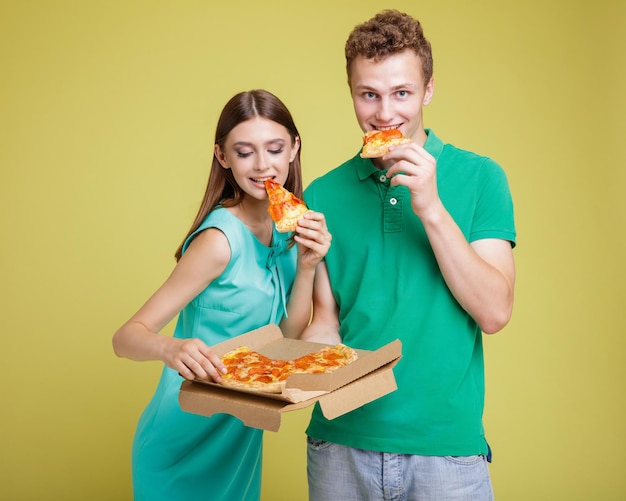 beau couple d'hommes et de femmes en robe bleu aqua, polo, souriant en mangeant de la pizza dans une boîte