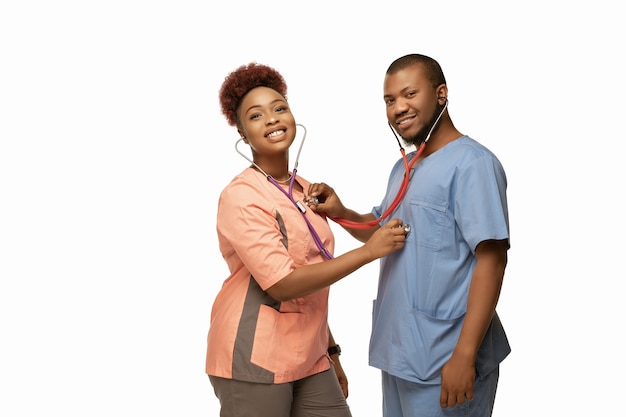 Beau couple de jeunes médecins afro-américains avec stéthoscopes souriant isolé sur blanc