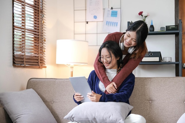 Beau couple de lesbiennes asiatiques étreignant leur petit ami dans le salon