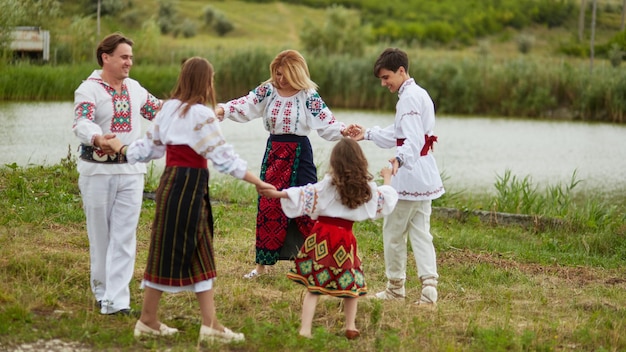 Beau couple avec leurs enfants vêtus de costumes traditionnels dansant ensemble la danse roumaine nationale