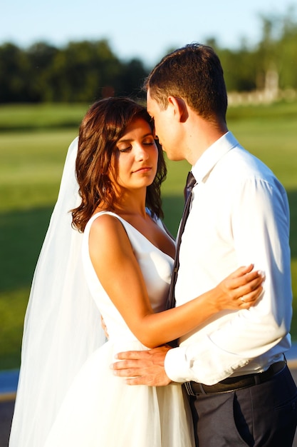 Beau couple de mariage au coucher du soleil Mariée marié en tenue de mariage avec bouquet de fleurs Romantique