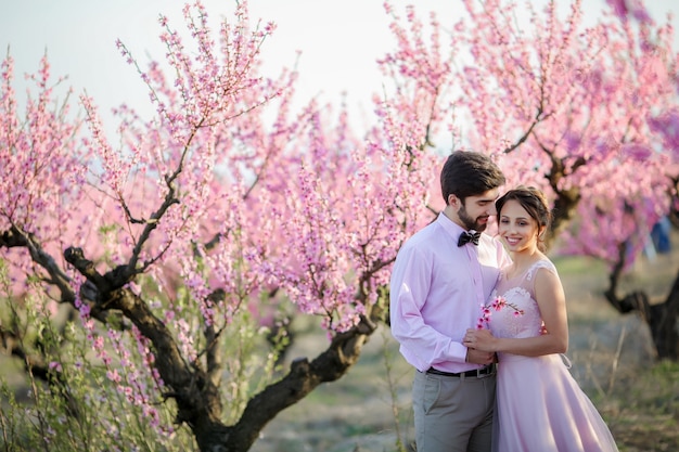 Beau couple de mariage dans les jardins d'une pêche en fleurs