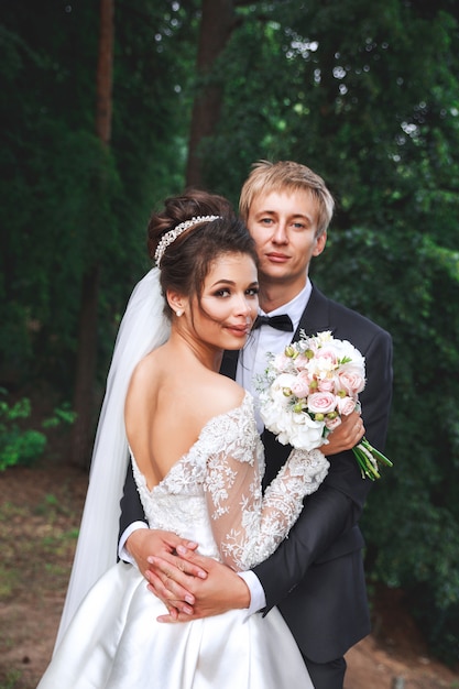 Beau couple de mariage dans le parc. Les mariés s'embrassent en plein air