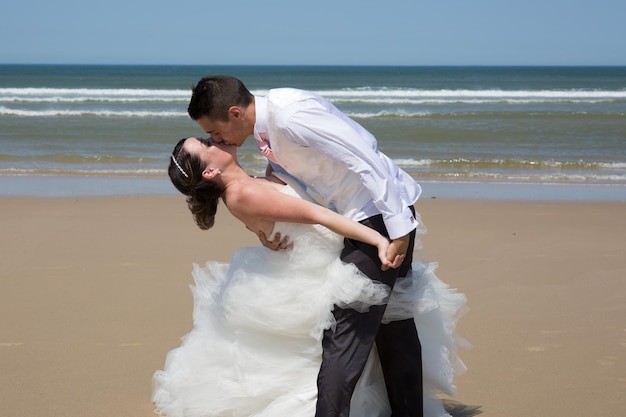 Beau couple de mariage à la plage avec robe de mariée