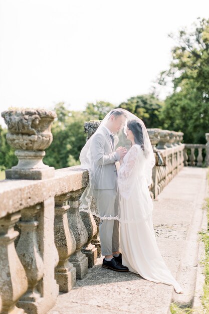 Beau couple de mariage romantique de jeunes mariés étreindre et main dans la main près de vieilles balustrades du château