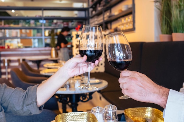 Beau couple de mariage avec des verres de vin rouge dans un pub-restaurant, grillant pour célébrer le concept de temps libre