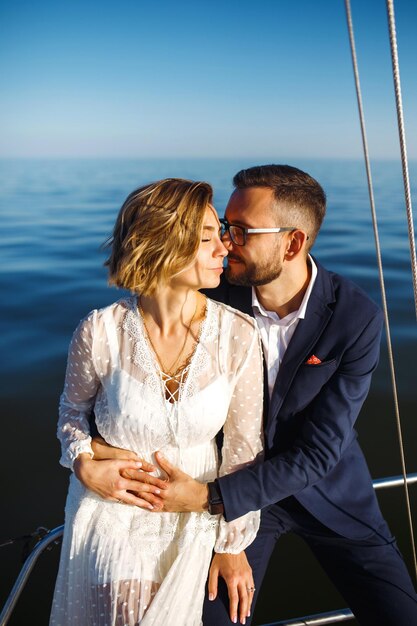 Photo beau couple de mariés sur un yacht le jour du mariage à l'extérieur dans la mer ensemble le jour du mariage