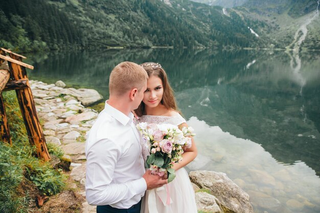 Un beau couple moderne près d'un lac dans les montagnes fait des photos de mariage