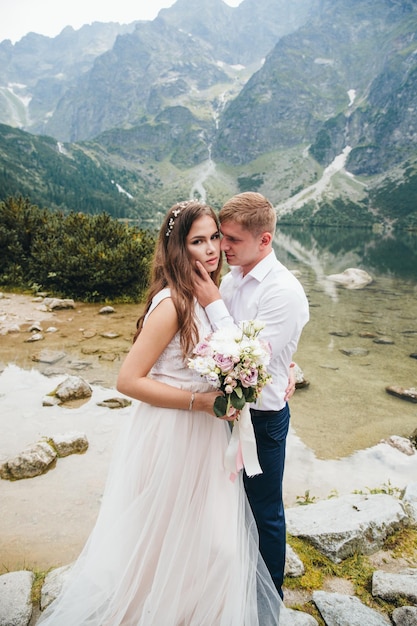 Un beau couple moderne près d'un lac dans les montagnes fait des photos de mariage