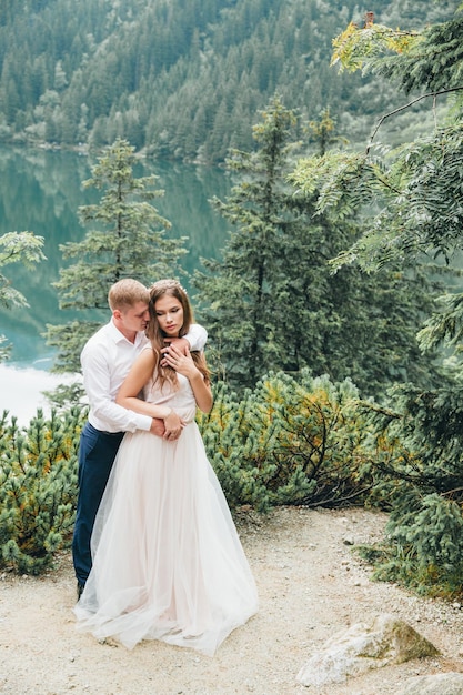 Un beau couple moderne près d'un lac dans les montagnes fait des photos de mariage