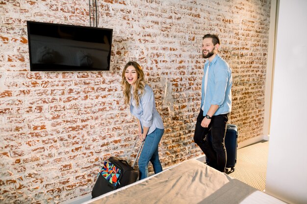 Beau couple passant un week-end romantique ou un voyage d'affaires, ouvrant la porte d'une chambre d'hôtel moderne