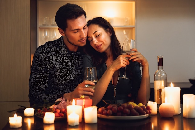 Beau couple passionné ayant un dîner romantique aux chandelles à la maison, boire du vin, griller