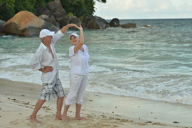 Beau couple de personnes âgées heureux dansant au complexe tropical