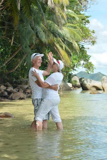 Beau couple de personnes âgées heureux dansant au complexe tropical