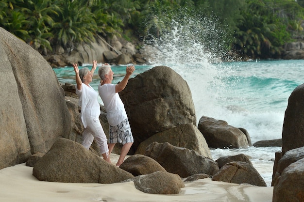 Un beau couple de personnes âgées heureux se repose dans un complexe tropical avec les mains en l'air