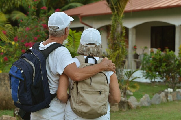 Un beau couple de personnes âgées heureux se repose dans un complexe tropical avec des sacs à dos