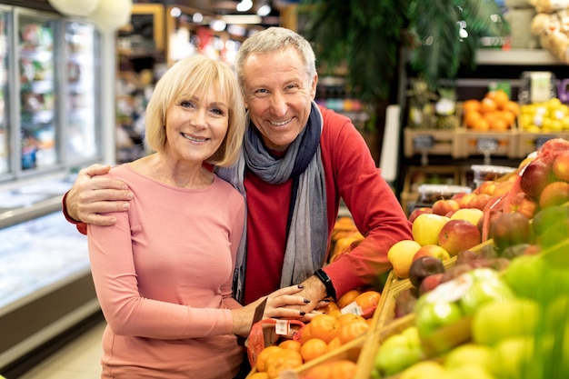 Beau couple de personnes âgées posant dans un espace de copie de supermarché