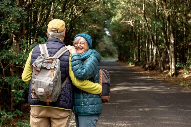 Beau couple de personnes âgées profitant de la nature en plein air dans une forêt de montagne marchant sur la route Joyeux couple de personnes âgées avec des sacs à dos voyageant ensemble dans le parc national de Garajonay de La Gomera