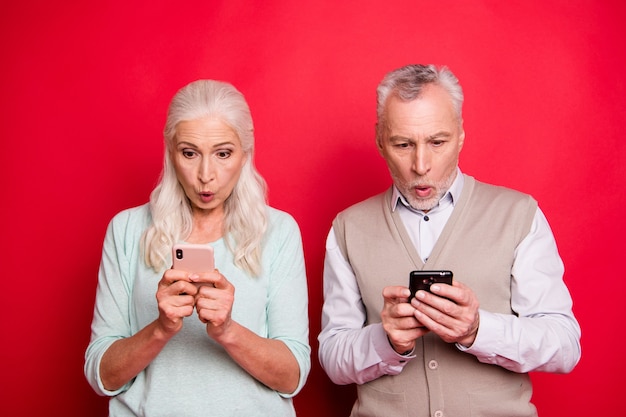 Beau couple plus âgé posant ensemble contre le mur rouge