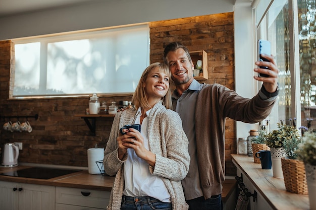 Beau couple prenant une photo à la cuisine