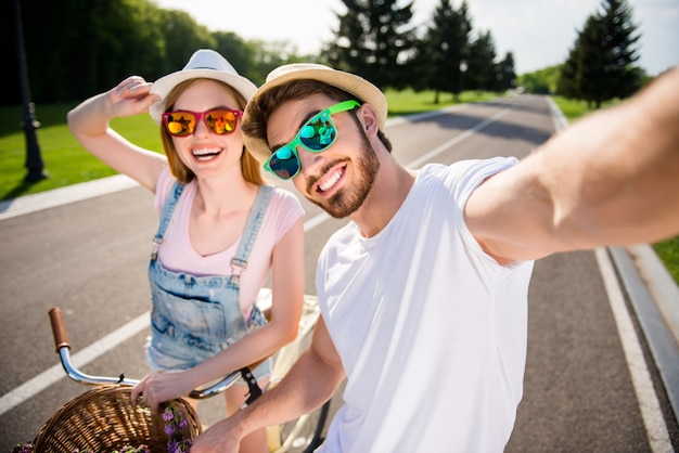 Beau couple prenant selfie ensemble à l'extérieur avec des vélos