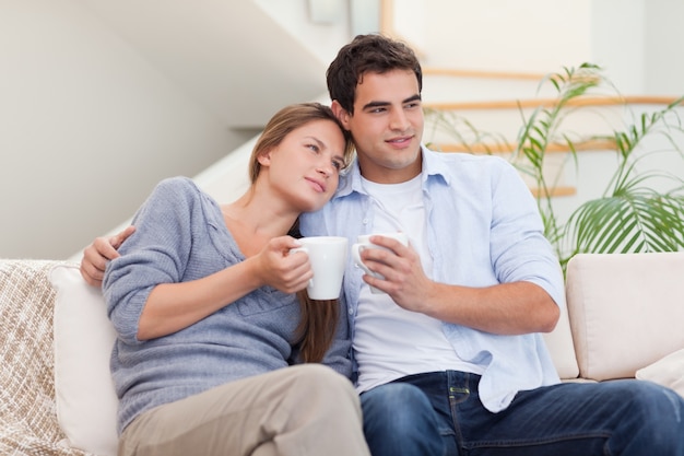 Beau couple en regardant la télévision tout en buvant du café