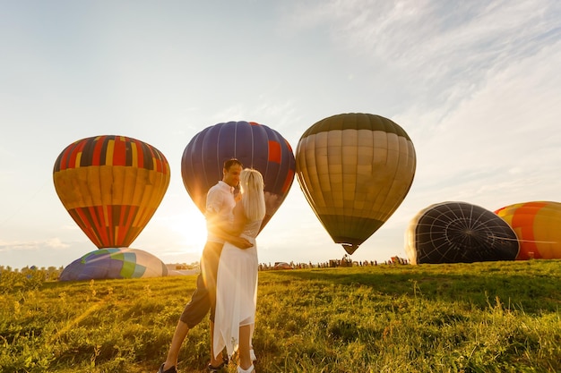 Beau couple romantique étreignant au pré. ballon à air chaud sur un arrière-plan