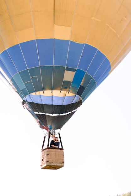 Beau couple romantique étreignant dans le panier de montgolfière, volant en soirée ensoleillée d'été