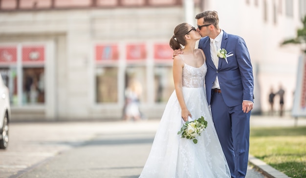 Beau couple s'embrassant au milieu de la ville. Ils viennent de se marier et se font prendre en photo pour l'album.