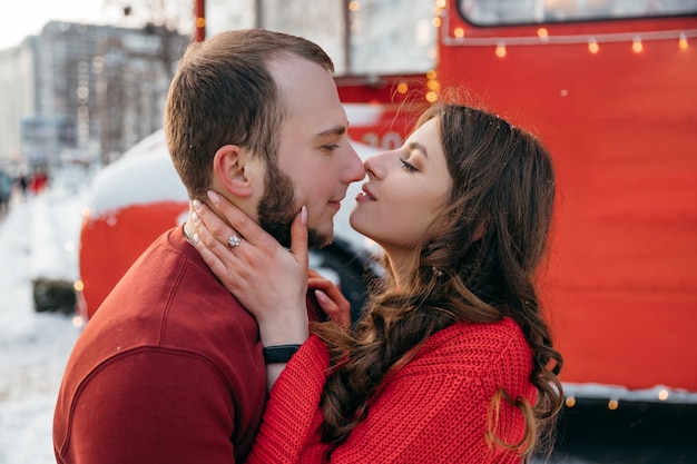 Beau couple s'embrasse sur le fond d'un bus rouge. Photo de haute qualité