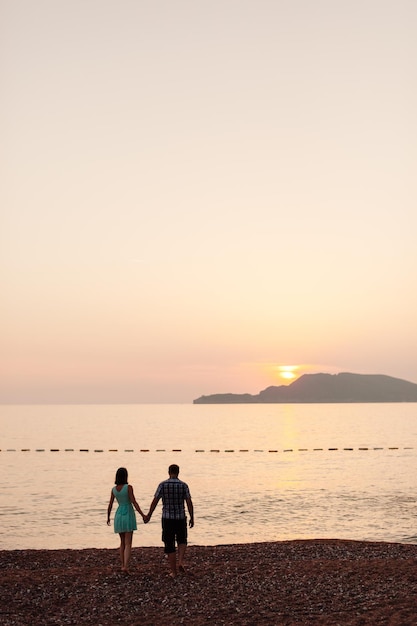 Beau couple se détendre dans le parc avec la silhouette de la lumière du soleil Coucher de soleil avec vue sur la mer