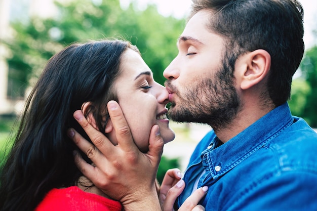 Un beau couple souriant amoureux marche ensemble. Femme et homme s'embrassent, s'embrassent et s'amusent ensemble dans le parc en plein air