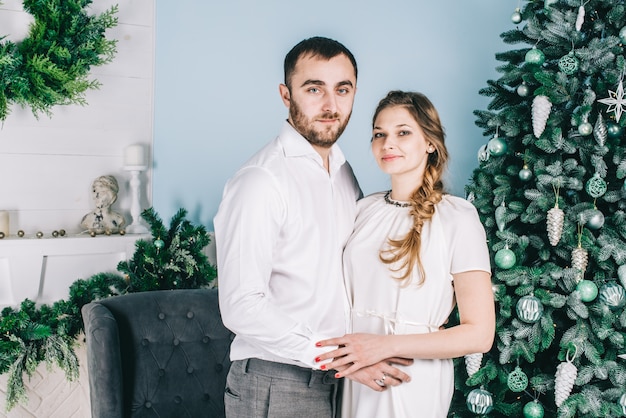 Photo beau couple souriant romantique se trouve près de l'arbre de noël