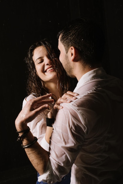 Beau couple sous la pluie la nuit, vue romantique, couple marchant et s'embrassant.