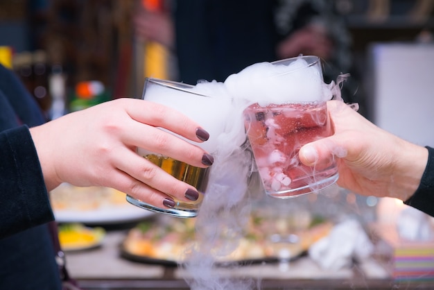 Beau couple tenant des cocktails de glace sèche à la fête.