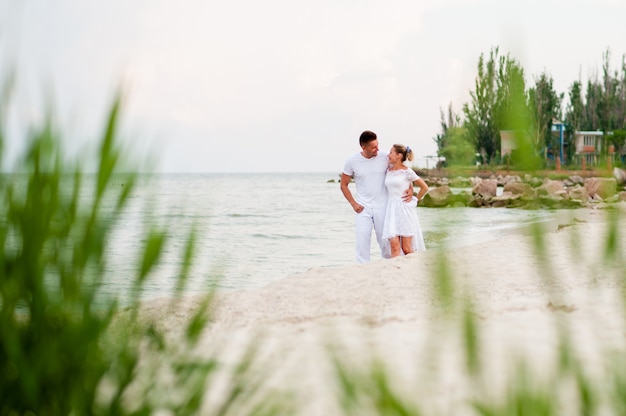 Beau couple en vêtements blancs marchant sur la mer