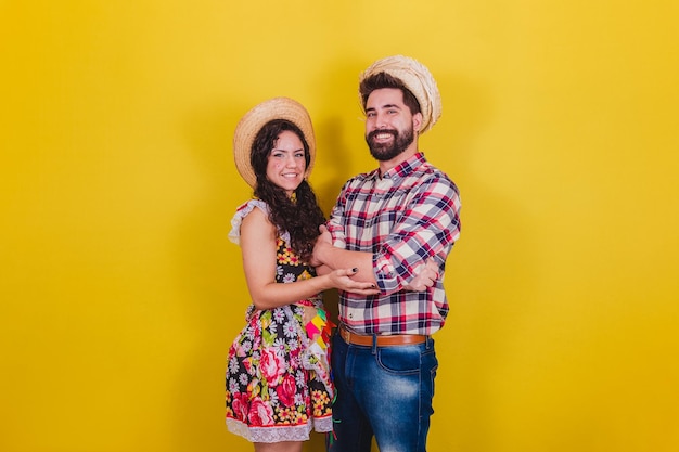 Beau couple vêtu de vêtements typiques pour une Festa Junina Arraia de Sao Joao avec les bras croisés