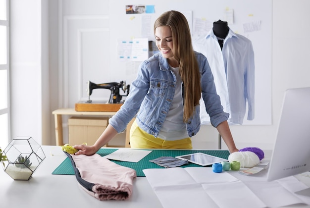 Beau créateur de mode debout près du bureau en studio