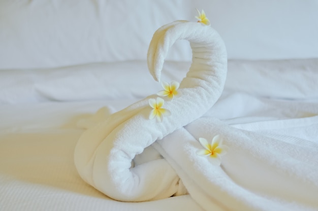 Beau cygne de serviette de bain blanche décorer sur un lit blanc. serviette cygne avec des fleurs topiques - frangipanier. Bon accueil de l'hôtel.