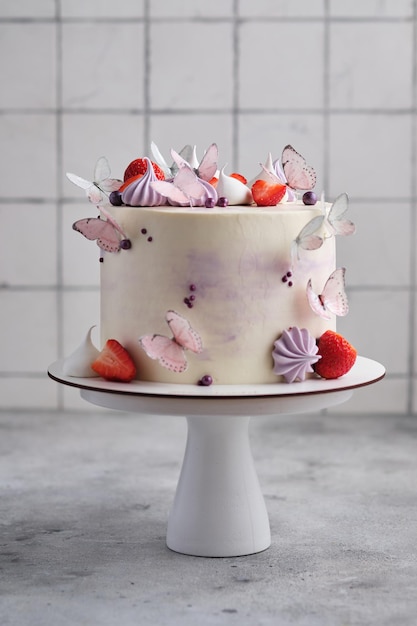 Beau et délicat gâteau aux fraises pour une fille. Le dessert est décoré de fraises fraîches, de meringues et de papillons.