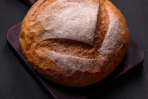 Beau délicieux pain blanc de forme ronde fraîchement cuit sur un fond de béton foncé