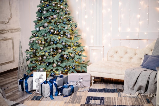 Beau design de chambre moderne et chaleureux dans des couleurs claires et douces décorées d'un arbre de Noël et d'éléments de décoration pour la nouvelle année