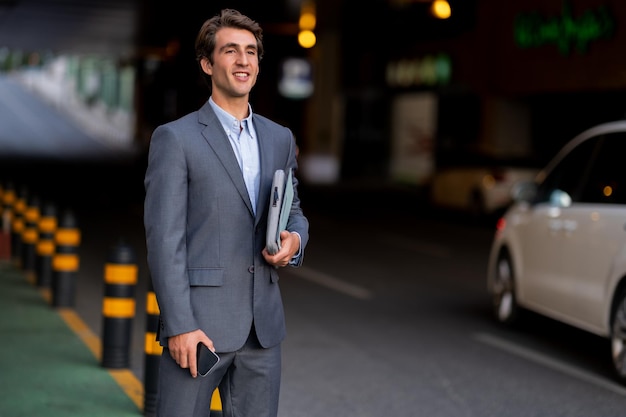 Un beau directeur général se tient au parking en attendant la voiture.