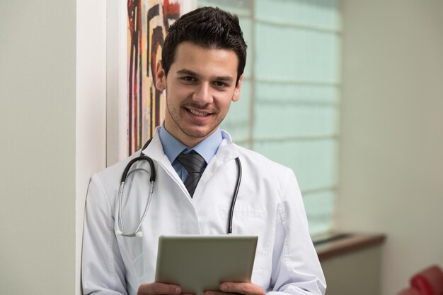 Beau docteur regardant son écran d'ordinateur dans son bureau