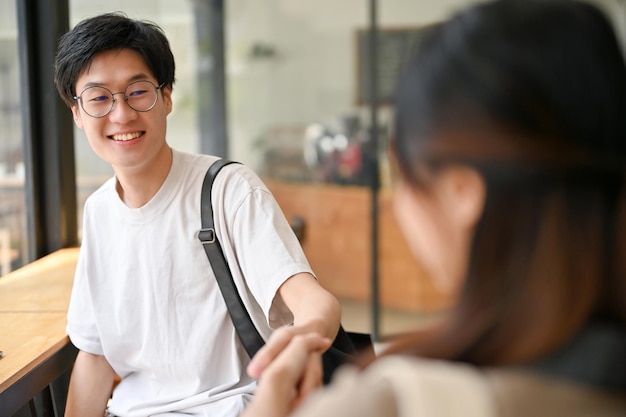 Beau étudiant masculin asiatique serrant la main d'une amie